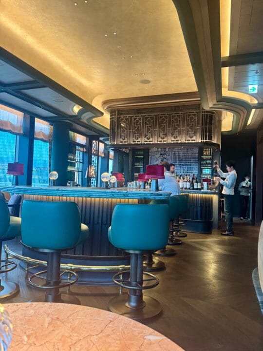 Canes & Tales店内。中央に置かれた島型のバーカウンターとターコイズの椅子