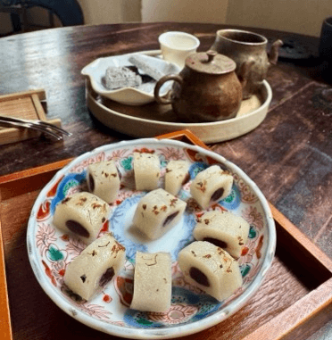 木の丸テーブルに置かれた茶器一式と、絵皿に丸く並べられた白い茶菓子