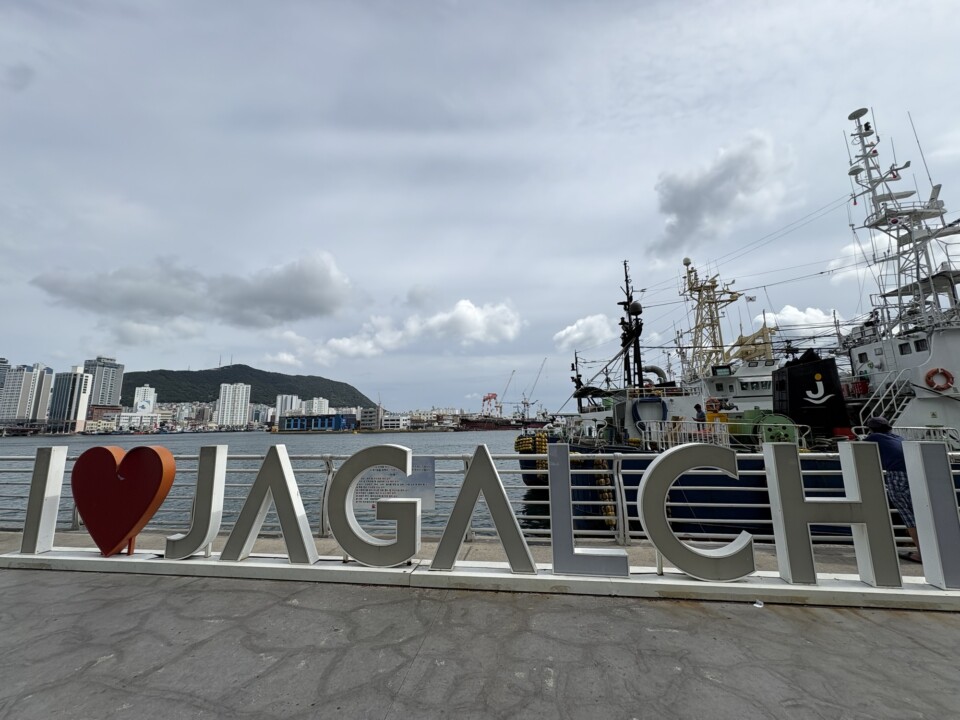 チャガルチ市場前の「I♥JAGALCHI」モニュメントと釜山港の漁船