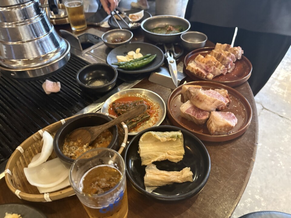 焼き台を囲む多彩な副菜。青唐辛子とにんにく、キムチ、豆腐皮、薬味だれなど