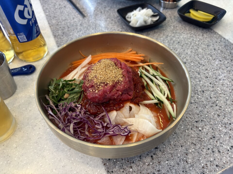 ユッケをのせたビビン系のミルミョン。千切り野菜と辛だれを混ぜていただく