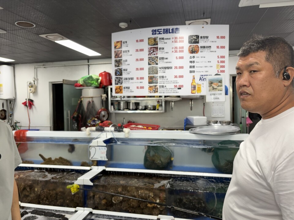 「影島海女村」のメニュー看板。アワビ小30,000ウォン、ウニ10,000ウォンなど時価の海鮮が並ぶ