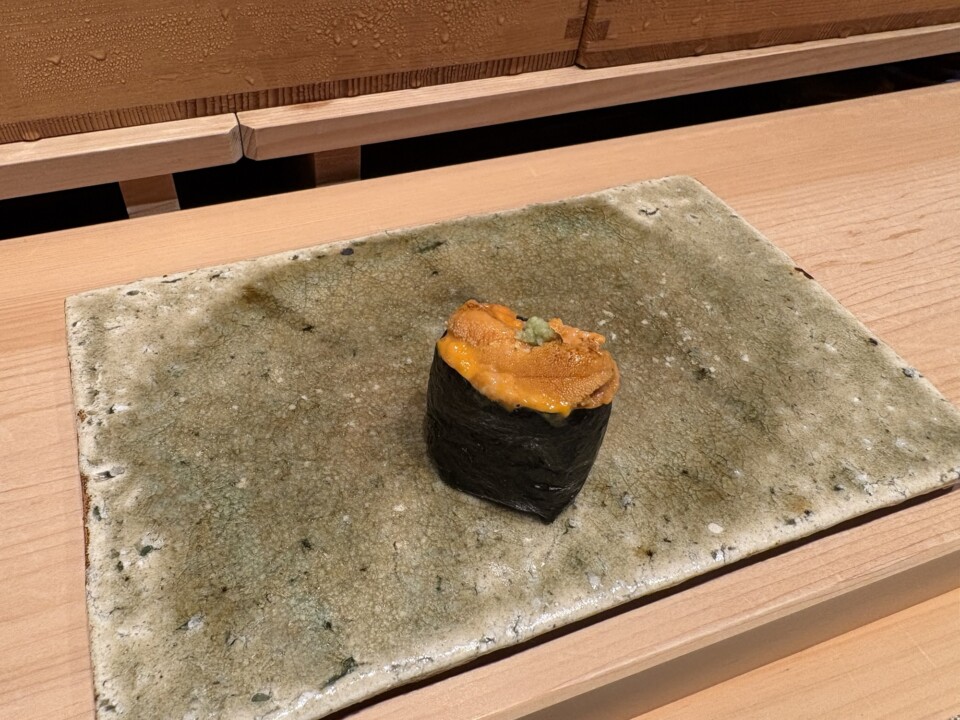 焼海苔で巻いたウニの軍艦が、緑がかった石肌の器にひとつだけ置かれている