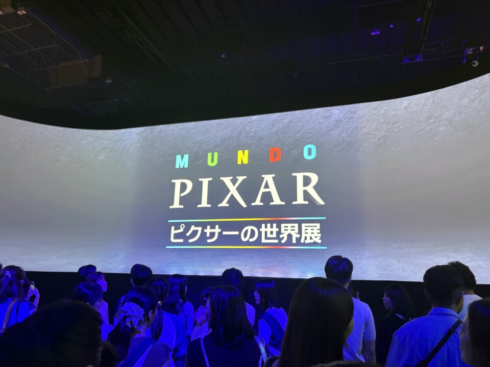 MUNDO PIXAR ピクサーの世界展の導入映像が映るスクリーンと来場者