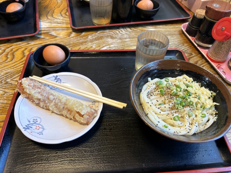 釜バターうどんと、揚げ物をのせた皿。テーブルには生卵
