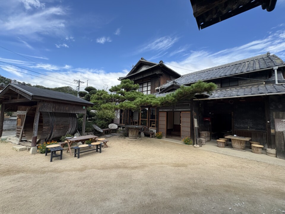 青空の下に建つヤマロク醤油の古い日本家屋と、中庭のテーブル席