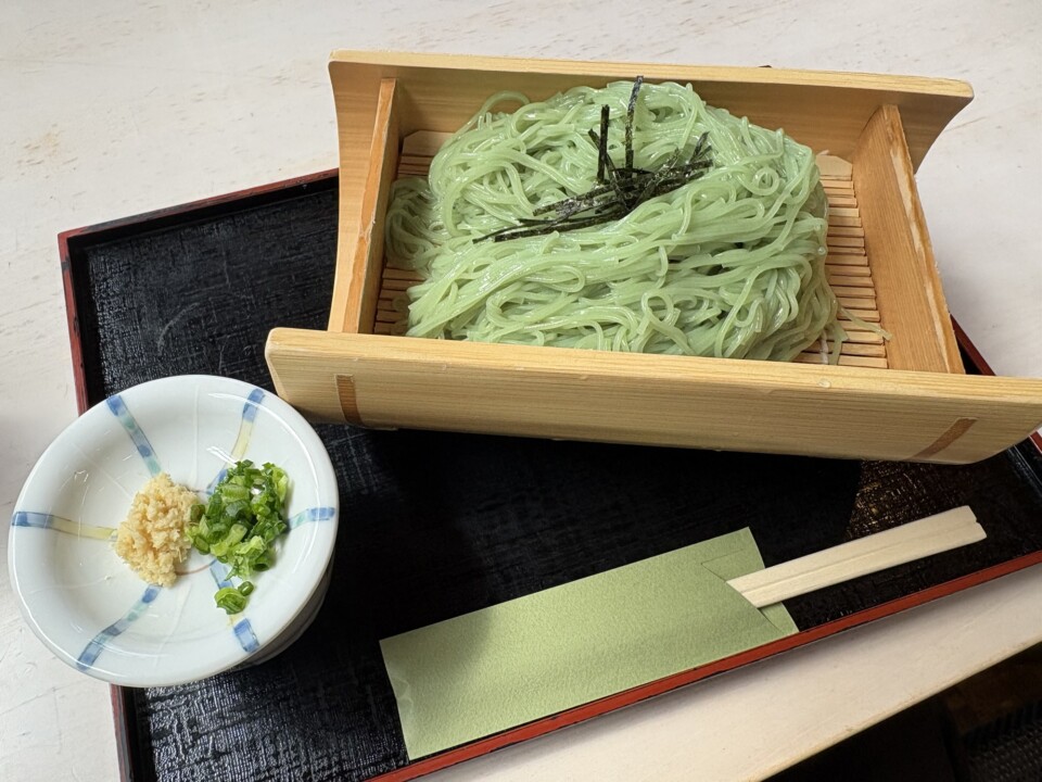 木の器に盛られた緑色のオリーブ素麺と、ねぎ・しょうがの薬味