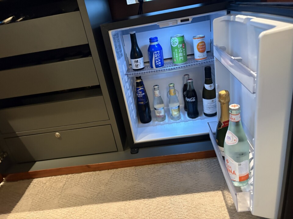 客室の冷蔵庫。日本酒、ソフトドリンク、ミネラルウォーター、ワインのボトルが並ぶ